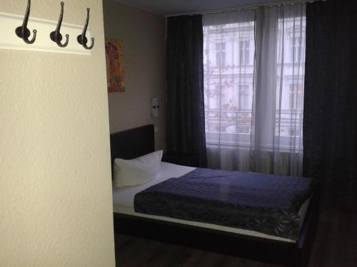 een kleine slaapkamer met een bed en een raam bij Pension Levi in Berlijn