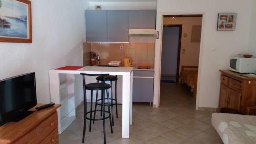 une cuisine avec un comptoir et deux tabourets de bar dans l'établissement studio bord de mer, à Saint-Mandrier-sur-Mer