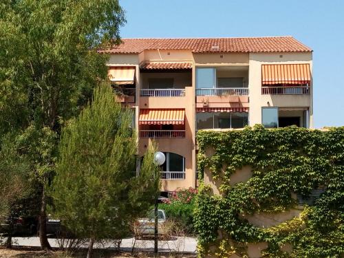 un grand immeuble d'appartements avec des arbres devant lui dans l'établissement studio bord de mer, à Saint-Mandrier-sur-Mer