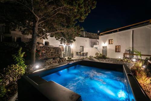 a swimming pool in the yard of a house at night at Noelia Suites in Oia