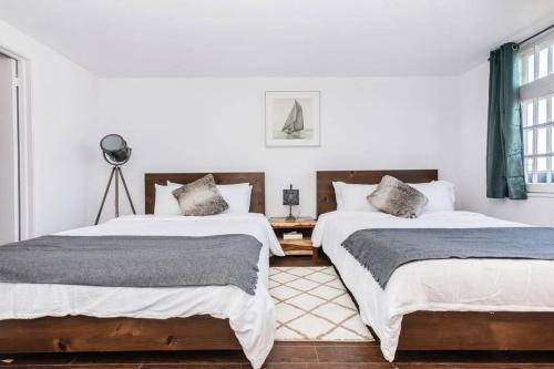 2 camas en una habitación con paredes blancas en Modern Meets Rustic- 2 Bedroom in Old Quebec, en Quebec