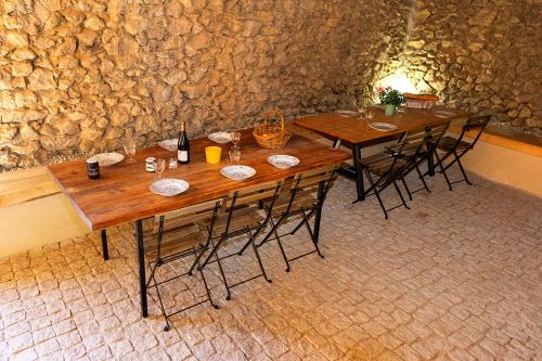 2 mesas de madera con sillas y una pared de piedra en Rouretord La Rainette, en Gilhac-et-Bruzac