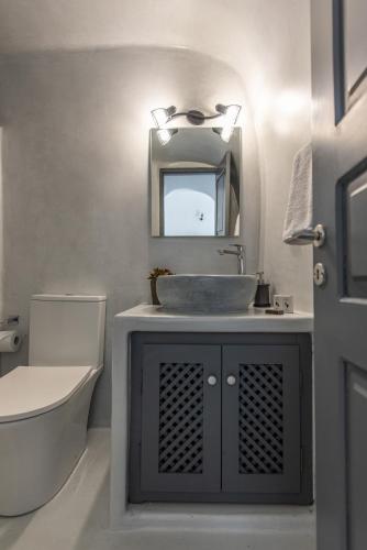 a bathroom with a sink and a mirror and a toilet at Noelia Suites in Oia