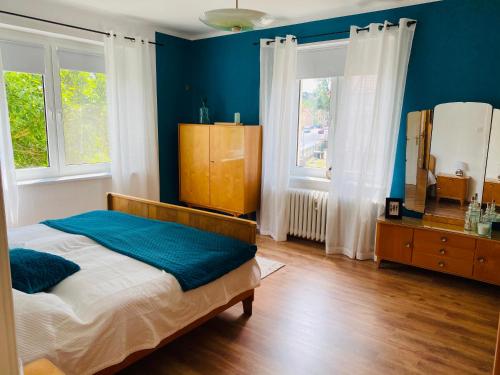 a bedroom with a bed with blue walls and windows at Ferienwohnung „Lena“ in Meißen