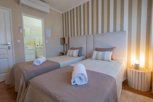 een slaapkamer met 2 bedden en handdoeken bij Casa da Praia in Zambujeira do Mar