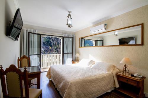 um quarto com uma cama, um espelho e uma televisão em Hotel Nevada em Campos do Jordão
