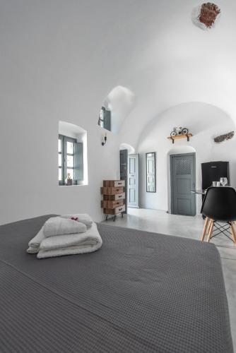 a bedroom with white walls and a bed with a black rug at Noelia Suites in Oia