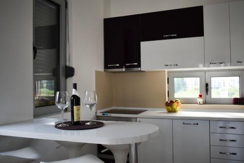 biała kuchnia z białym stołem i kieliszkami do wina w obiekcie Lux Kalimera Apartments w Ulcinju