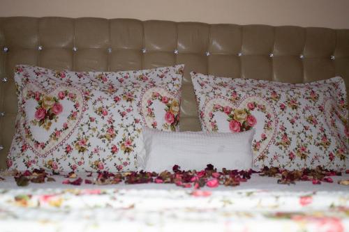 a bed with red and white pillows and flowers on it at Hotel Living in Šuto Orizari