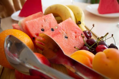 a bowl of fruit with watermelon oranges bananas and grapes at Hotel Living in Šuto Orizari
