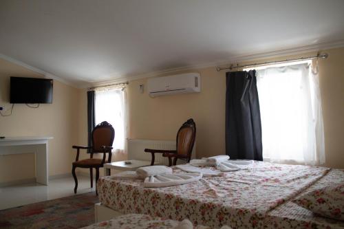 a bedroom with a bed and two chairs and a window at Hotel Living in Šuto Orizari