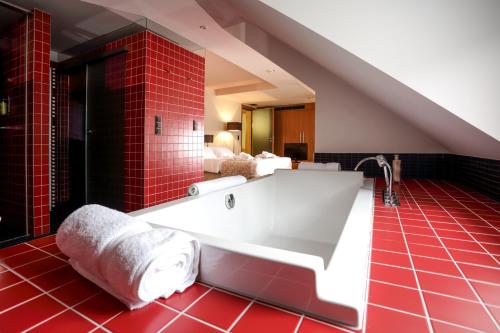 ein Badezimmer mit einer großen Badewanne mit roten Fliesen in der Unterkunft Hotel-Résidence Am Klouschter in Mondorf-les-Bains