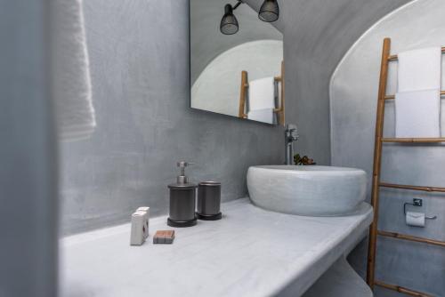 a white bathroom with a sink and a mirror at Noelia Suites in Oia