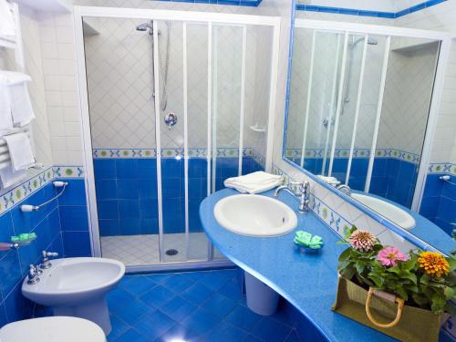 bagno blu con lavandino e doccia di Hotel Ambasciatori a Ischia