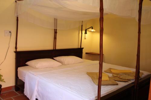 1 dormitorio con cama con dosel y sábanas blancas en Gite Nam Hien Mekong, en Cho Lach