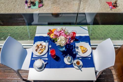 a table with plates of food and flowers on it at White Bay in Fontane Bianche