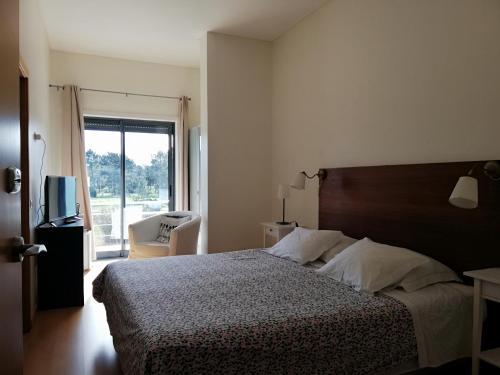Alojamento Local Verde e Mar في كومبورتا: غرفة نوم بسرير ونافذة كبيرة