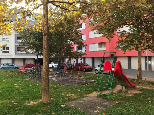 plac zabaw w parku przed różowym budynkiem w obiekcie Bizi Green - Zagreb South w Zagrzebiu