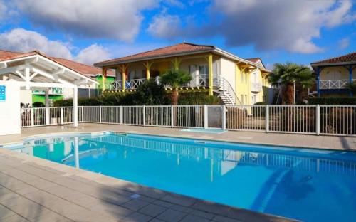 a swimming pool in front of a house at LILLOT GREEN Appartement in Sanguinet