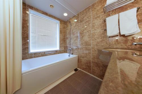 a bathroom with a bath tub and a window at Hotel BB Fast Sakuranbo Higashine in Higashine