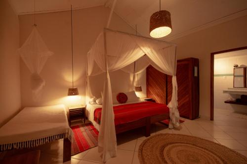 a bedroom with a canopy bed and a red rug at Na Villa dos Algodões in Marau