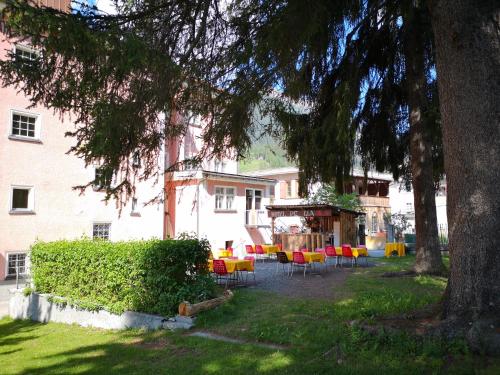 um quintal com cadeiras e uma mesa em frente a um edifício em Historisches Italienisches Hotel Piz Ela Bergün em Bergün