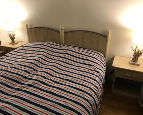 - un lit avec une couverture rayée dans une chambre dans l'établissement Charmant appartement au cœur de Juan les Pins, à Antibes