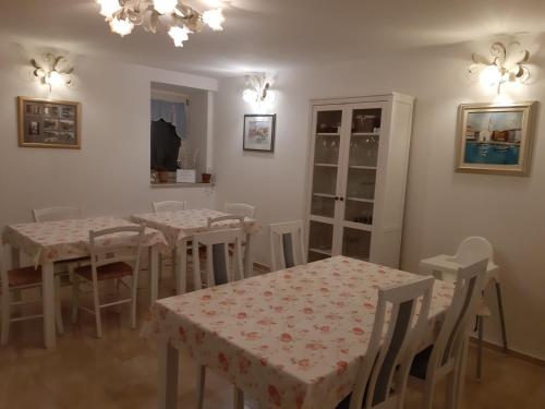 a dining room with white tables and chairs and a chandelier at Villa Claudia in Fažana