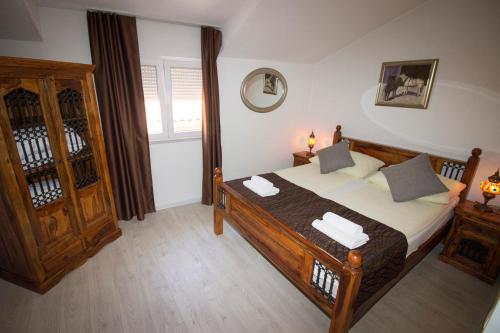 a bedroom with a wooden bed with towels on it at Hotel Villa Nadin in Mostar