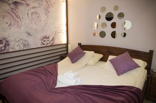 a bed with white sheets and purple pillows at Hotel Villa Nadin in Mostar
