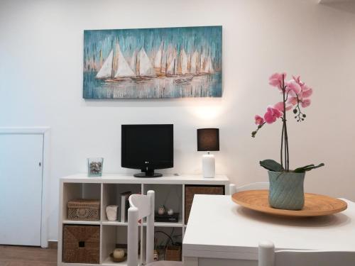 - un salon avec une télévision et un vase de fleurs dans l'établissement Il Tucano - Taormina, à Taormine