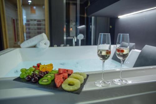 a plate of fruit and two glasses of wine at Love Suite Roma - Il Nido d'Amore in Rome