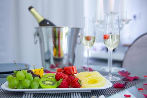 a plate of fruit on a table with wine glasses at Love Suite Roma - Il Nido d'Amore in Rome