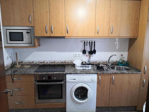 a kitchen with a washing machine and a microwave at Apartamento en casa Portonovo vacaciones in Portonovo