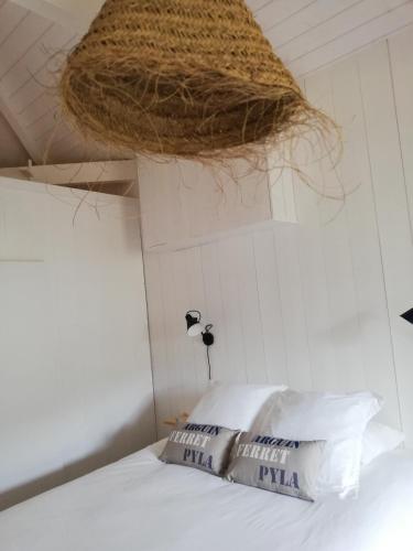 a room with a bed with a basket hanging from the ceiling at Centre Cap-ferret, les chambres du phare, océan in Bélisaire