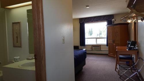 a room with a bed and a sink and a bathroom at Pines Motel in Hinton