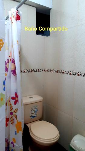a bathroom with a toilet and a shower curtain at Hostal Capac in Ayacucho