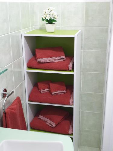 a towel rack with red towels and a vase of flowers at Chiara Naxos Apartment in Giardini Naxos