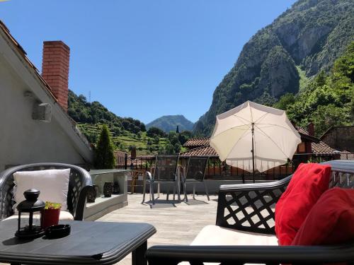 eine Terrasse mit einem Tisch und einem Sonnenschirm in der Unterkunft Posada La Cuadrona in La Hermida