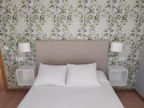 a bedroom with a white bed with two night stands at Apartamento F6 in Marín