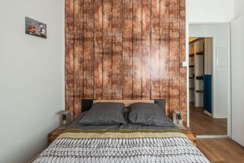 - une chambre avec un lit et un mur en bois dans l'établissement L'urbain Narbonnais, à Narbonne