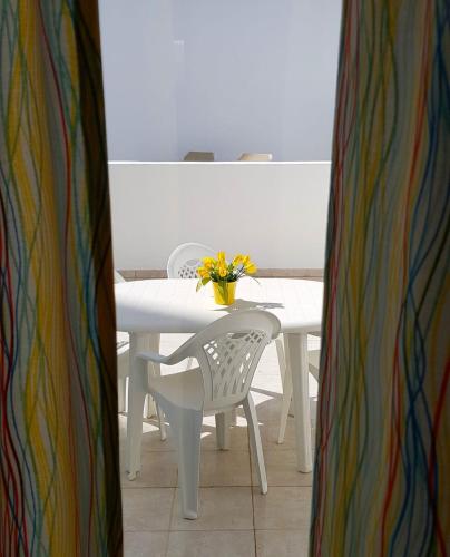 a white table with a white chair and a vase of flowers at Oura Ocean Front in Albufeira