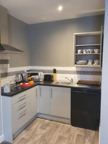 a kitchen with white cabinets and a black dishwasher at City Space in Doncaster