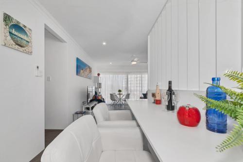 a white kitchen with a counter with bottles of wine at Studio 11 Mandurah Marina in Mandurah