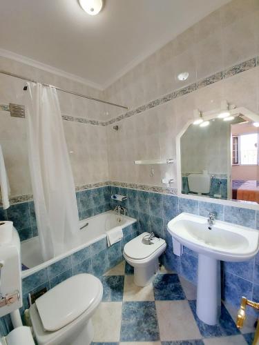 a bathroom with a toilet and a sink and a tub at VILA FORMOSA AL-Estabelecimento de Hospedagem,Quartos-Rooms in Monte Gordo