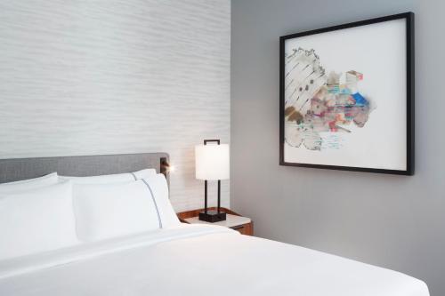 a white bed sitting next to a wall with a painting on it at Grand Hyatt at SFO in Millbrae