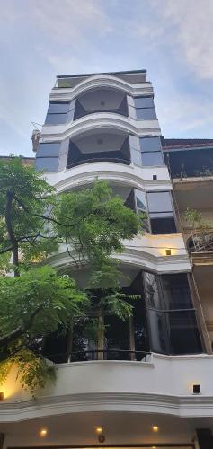 a tall white building with a tree in front of it at Hanoi Win Hotel & Travel in Hanoi