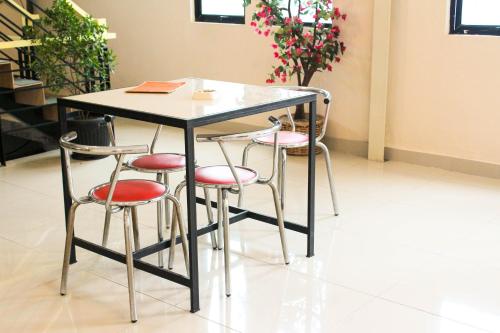 a table with four stools and a table and chairs at Intech Hostel in Bandung