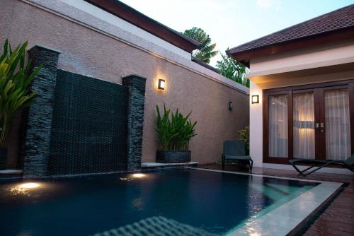 a swimming pool in front of a house at My Villas In Bali in Seminyak