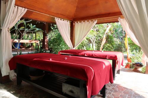 Dos camas en una habitación con colchas rojas. en Villa Aditya, en Tejakula